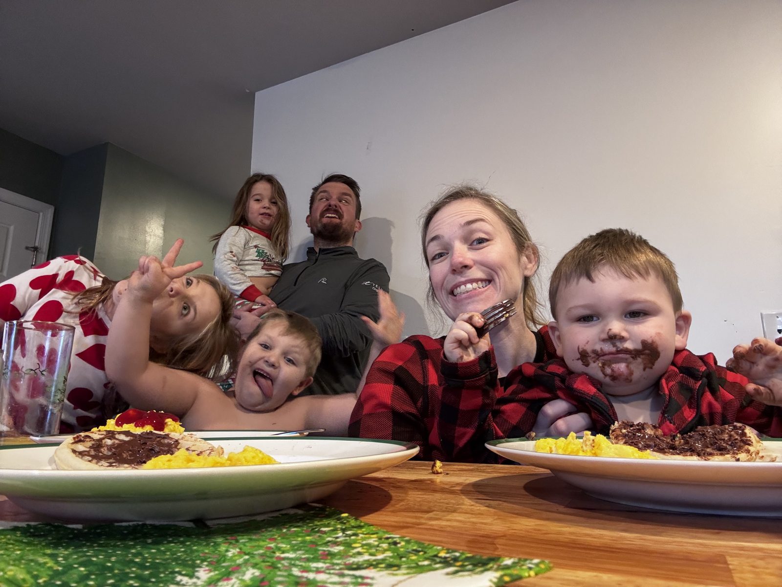 The whole family crowded around the breakfast table, pancakes and chocolate faces